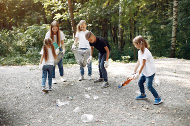 Çocuklar parktaki çöp torbalarında çöp topluyor.
