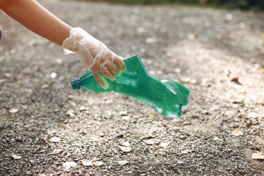 Kız parkta çöp torbaları topluyor.