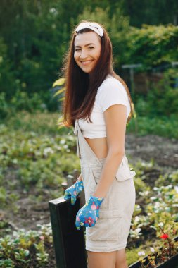 Güzel bir kadın evin yakınındaki bir bahçede çalışıyor.