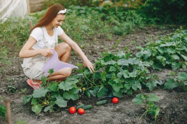 Güzel bir kadın evin yakınındaki bir bahçede çalışıyor.