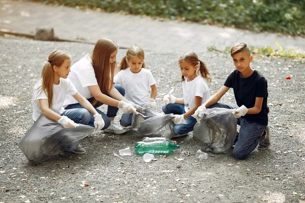 Crianças recolhem lixo em sacos de lixo no parque — Fotografia de Stock