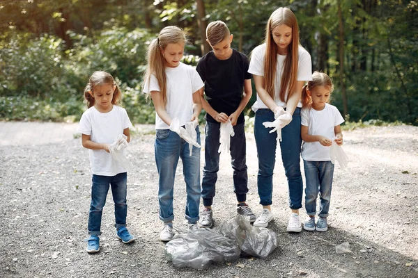 Crianças recolhem lixo em sacos de lixo no parque — Fotografia de Stock