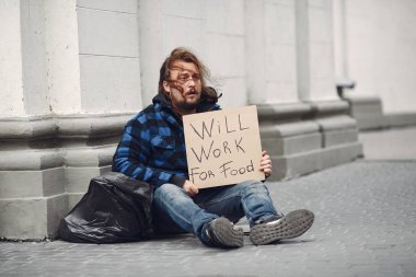 Güz şehrinde durgun elbiseli evsiz bir adam.