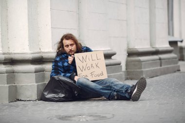 Güz şehrinde durgun elbiseli evsiz bir adam.