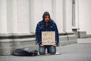 Güz şehrinde durgun elbiseli evsiz bir adam.