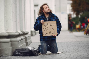 Güz şehrinde durgun elbiseli evsiz bir adam.