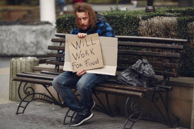 Güz şehrinde durgun elbiseli evsiz bir adam.