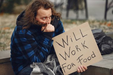 Güz şehrinde durgun elbiseli evsiz bir adam.