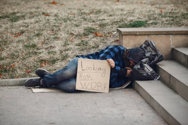 Güz şehrinde durgun elbiseli evsiz bir adam.