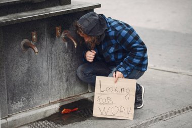 Güz şehrinde durgun elbiseli evsiz bir adam.