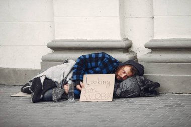 Güz şehrinde durgun elbiseli evsiz bir adam.