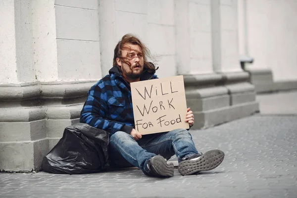 Güz şehrinde durgun elbiseli evsiz bir adam.