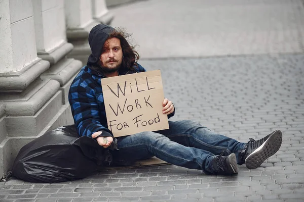Güz şehrinde durgun elbiseli evsiz bir adam.