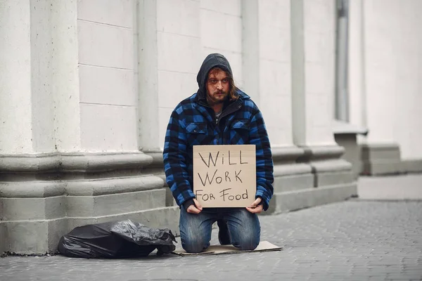 Güz şehrinde durgun elbiseli evsiz bir adam.