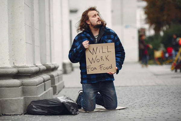 Güz şehrinde durgun elbiseli evsiz bir adam.