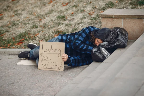 Güz şehrinde durgun elbiseli evsiz bir adam.