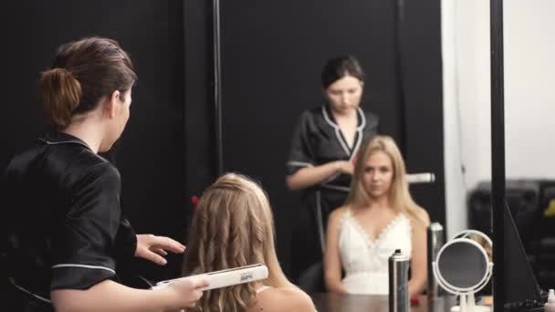 Frisör i svart uniform curling blont hår i salong — Stockvideo