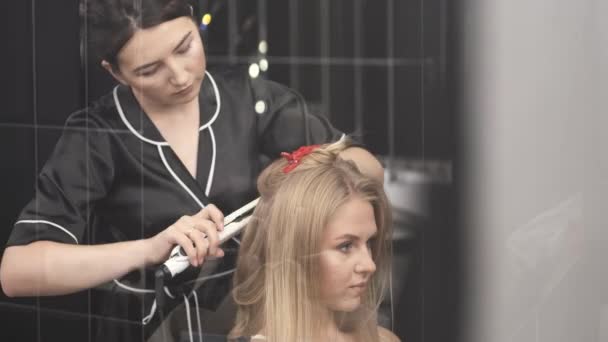Cabeleireiro em uniforme preto fazendo penteado para o cliente no salão — Vídeo de Stock