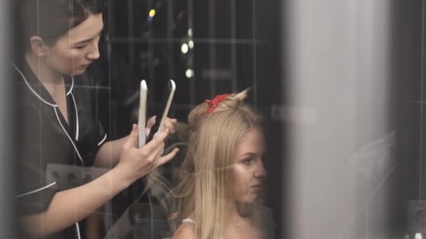 Cabeleireiro em uniforme preto fazendo penteado para o cliente no salão — Vídeo de Stock