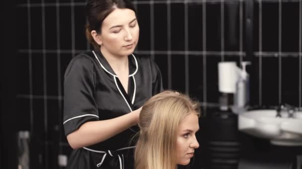 Cabeleireiro em uniforme preto fazendo penteado para o cliente no salão — Vídeo de Stock