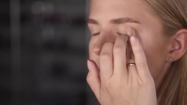 Artysta dotykając twarzy klientów podczas makijażu w salonie — Wideo stockowe
