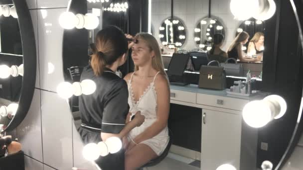 Artista y cliente en un proceso de maquillaje en el salón de belleza — Vídeos de Stock