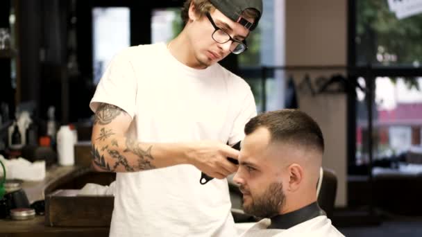 Barbeiro fazendo penteado para homem barbudo na barbearia — Vídeo de Stock