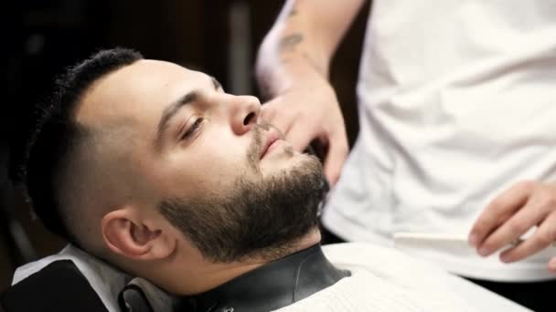 Fechar o processo de corte de barba de clientes por barbeiro na barbearia — Vídeo de Stock