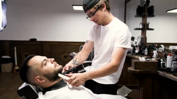 Peluquero en gorra negra clipping clientes barba en barbería . — Vídeos de Stock