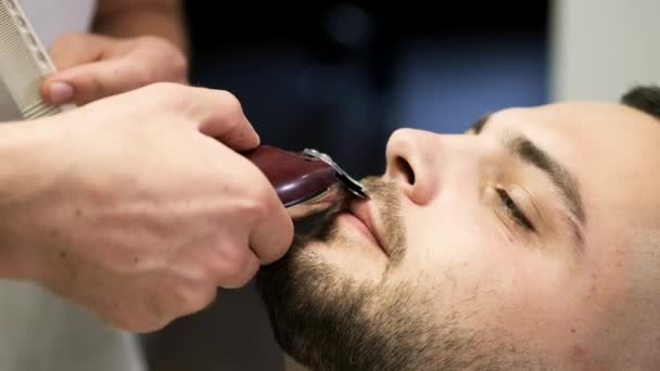 Barber clipping clients mustache with machine in barbershop — Stock Video