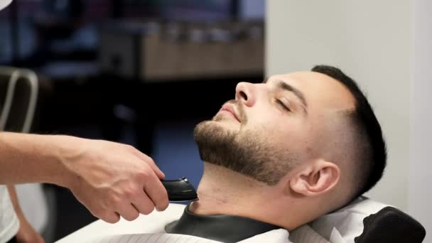 Sluiten van het proces van het snijden van klanten baard door kapper in kapperszaak — Stockvideo