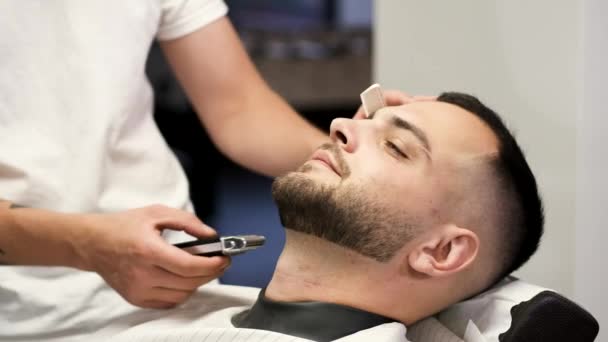 Закрытие процесса обрезки клиентом бороды парикмахером в парикмахерской — стоковое видео