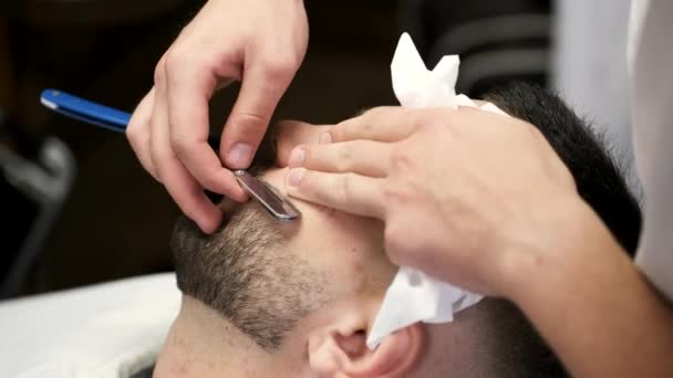 Sluiten van het proces van het snijden van klanten baard door kapper in kapperszaak — Stockvideo