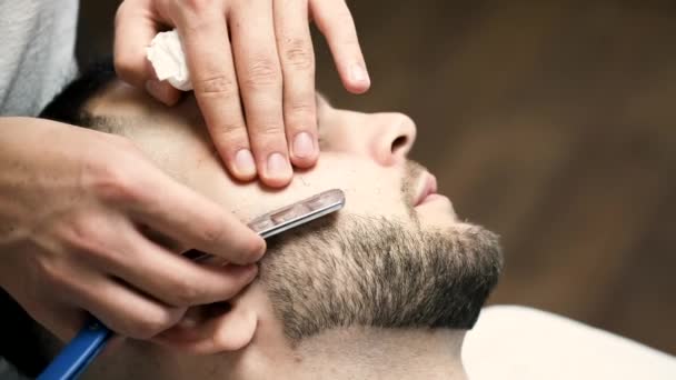 Primer plano del proceso de corte de barba de los clientes por peluquero en la barbería — Vídeo de stock