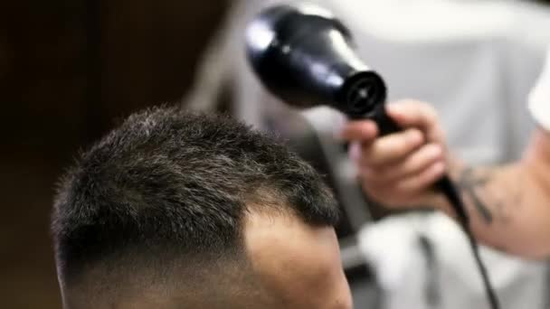 Kuaför, berber dükkanında saç kurutma makinesiyle müşterileri kurutuyor. — Stok video