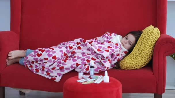 Menina doente descansando no sofá vermelho na sala de estar — Vídeo de Stock