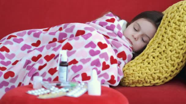 Άρρωστο κορίτσι ξεκουράζεται στον κόκκινο καναπέ στο σαλόνι — Αρχείο Βίντεο
