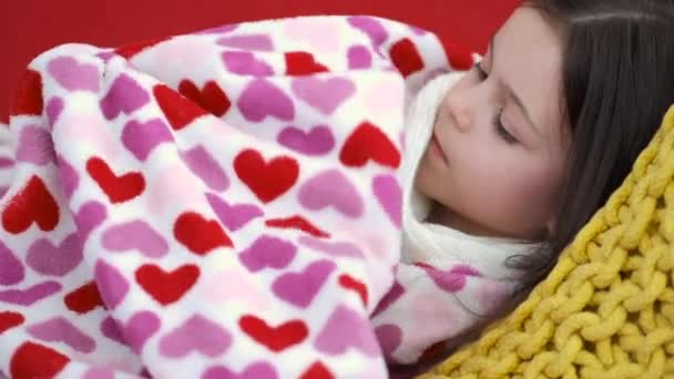 Sick girl resting on red couch in living room — Stock Video