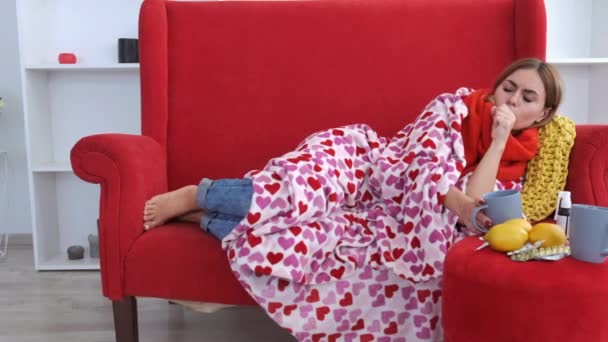 Chora kobieta z gorączką leżąca na czerwonej kanapie w domu — Wideo stockowe