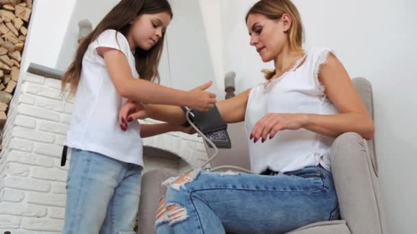 Hija ayudando a mamá a medir la presión con estetoscopio en casa — Vídeos de Stock