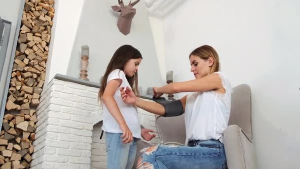 Hija ayudando a mamá a medir la presión con estetoscopio en casa — Vídeo de stock