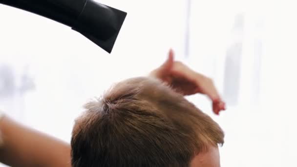 Парикмахер сушит клиентам волосы после стрижки в салоне — стоковое видео
