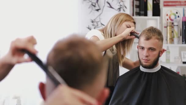 Hairdresser doing haircut for customer using scissors in salon — 비디오