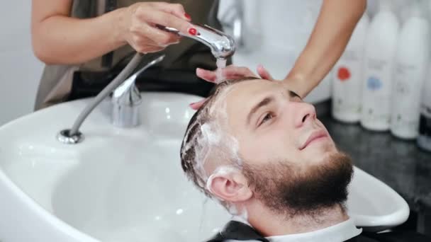 Парикмахер моет головы клиентам шампунем в салоне красоты — стоковое видео