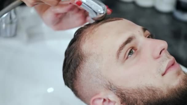 Парикмахер стирает клиентам голову в белой раковине в салоне красоты — стоковое видео