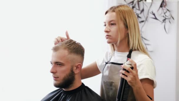 Estilista haciendo peinado con spray en salón de belleza — Vídeos de Stock