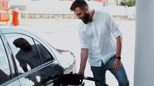 Bearded man in white shirt filling up his car — 비디오