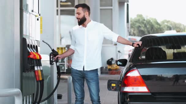 Όμορφος άνδρας στέκεται κοντά στο μαύρο αυτοκίνητο στο βενζινάδικο — Αρχείο Βίντεο