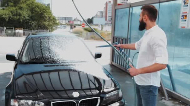 Chauffeur lave voiture noire avec tuyau au lavage de voiture — Video