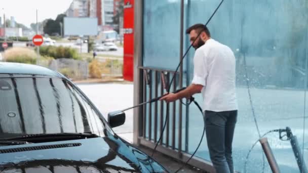 Chauffeur lave voiture noire avec tuyau au lavage de voiture — Video